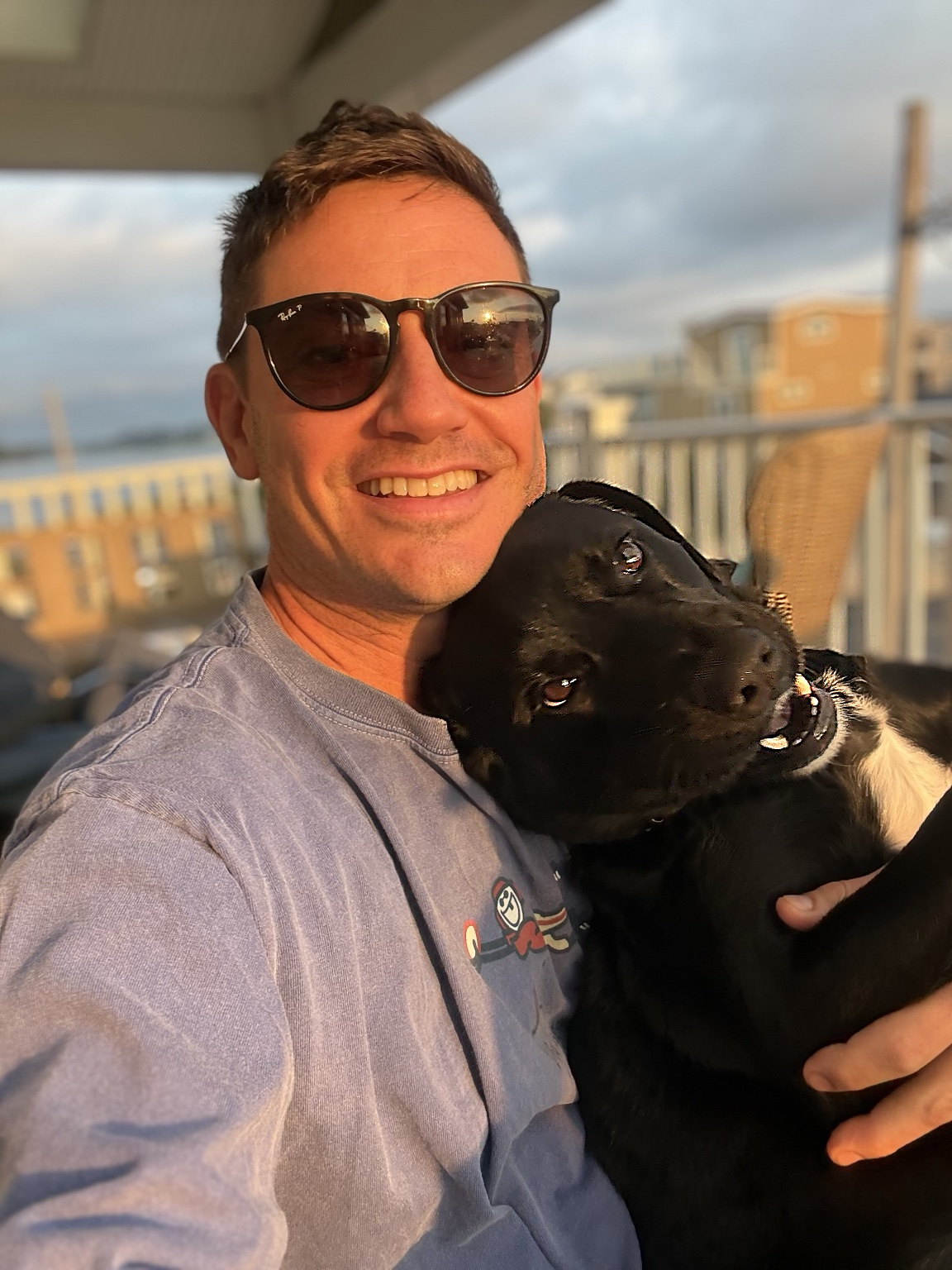 Nick Milak smiling with his dog Bubba in warm evening light